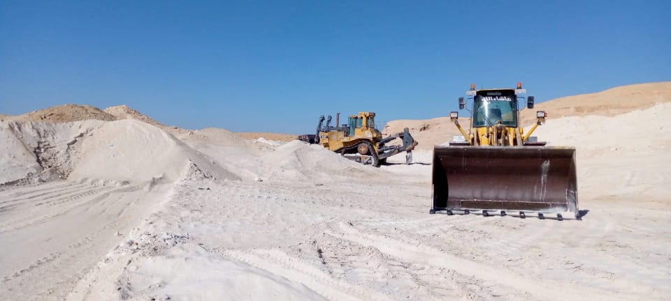 Two wheel loaders working at the white sand pile